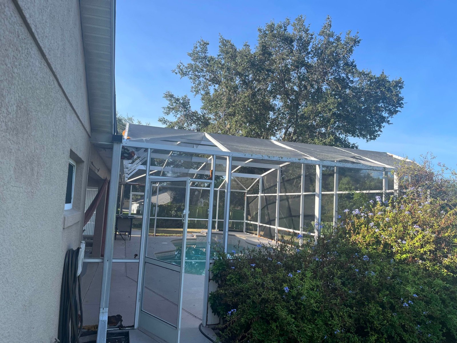 Damaged pool screen enclosure in Port Orange, Florida showing torn panels and aluminum frame – professional screen repair and rescreening service.