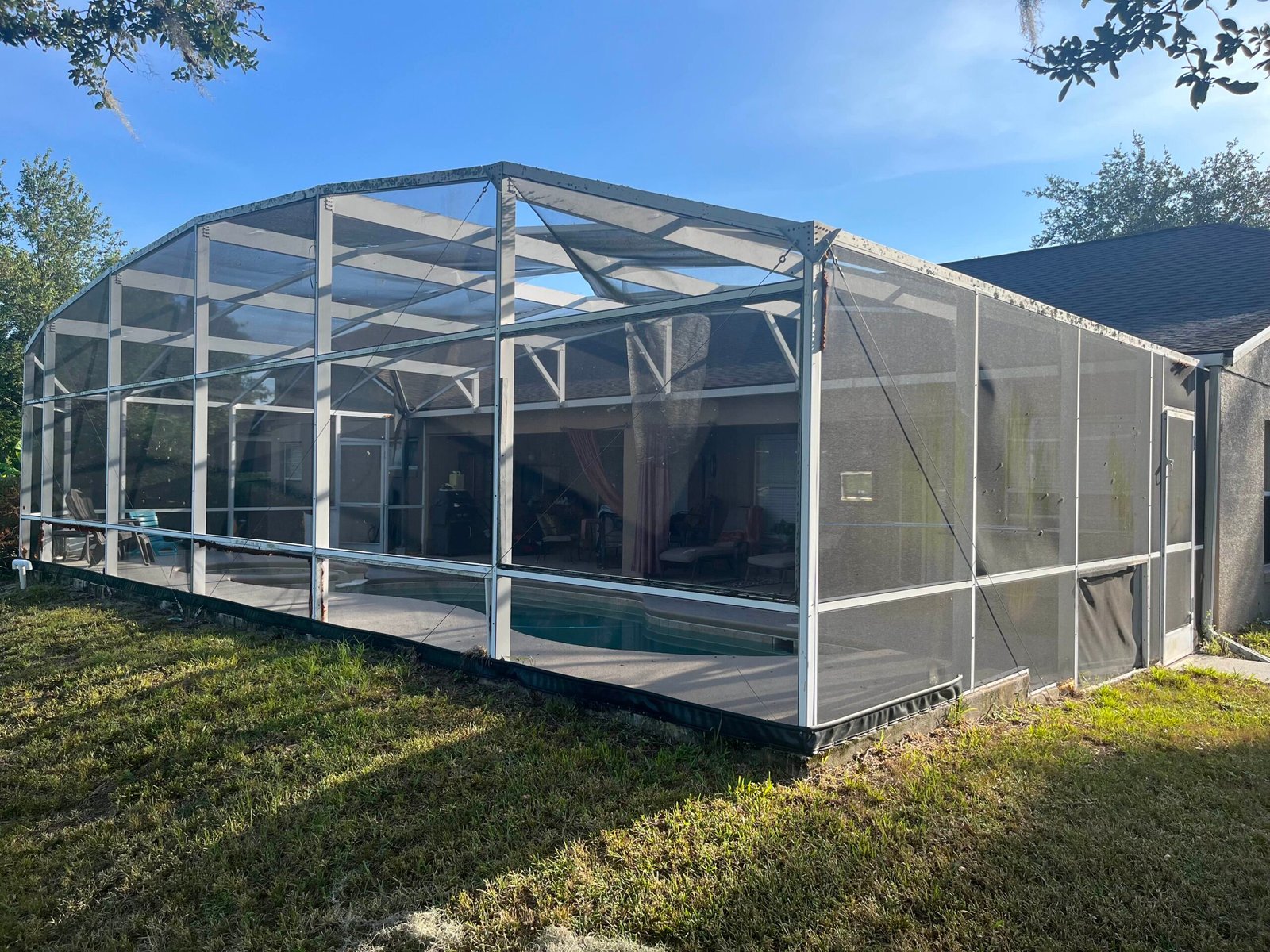 Large pool screen enclosure in Port Orange, Florida with aluminum frame and lanai screening – professional repair and rescreening services.